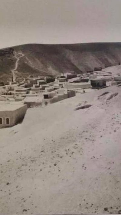 The village before the concrete. Flat-roofed mud-brick houses on a bare hillside, the path climbing behind.